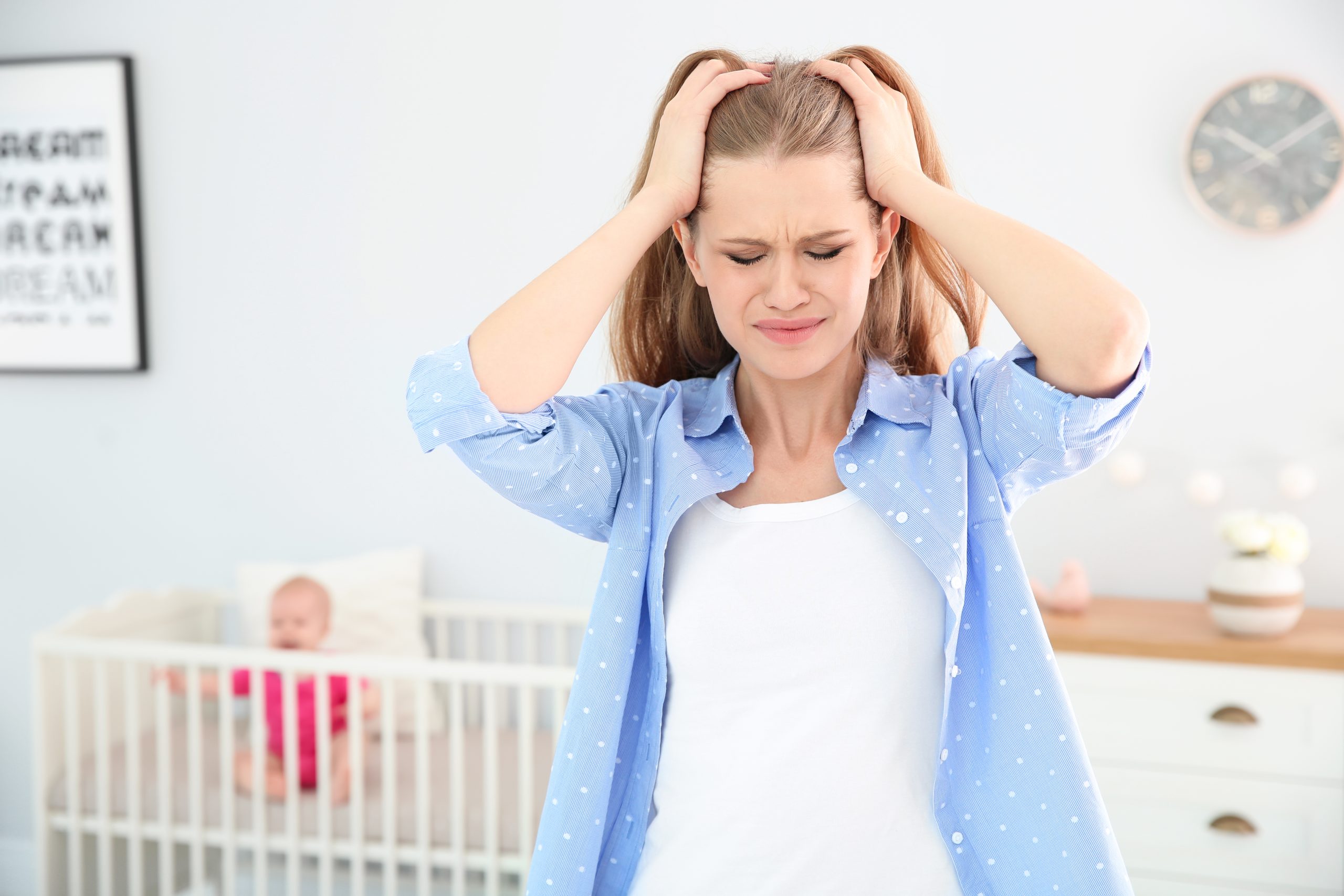 Maternal Mental Health: How to Manage the Mental Health Challenges of Being a Mum 3 Mother with post natal depression, hands in hair, baby in cot in the background