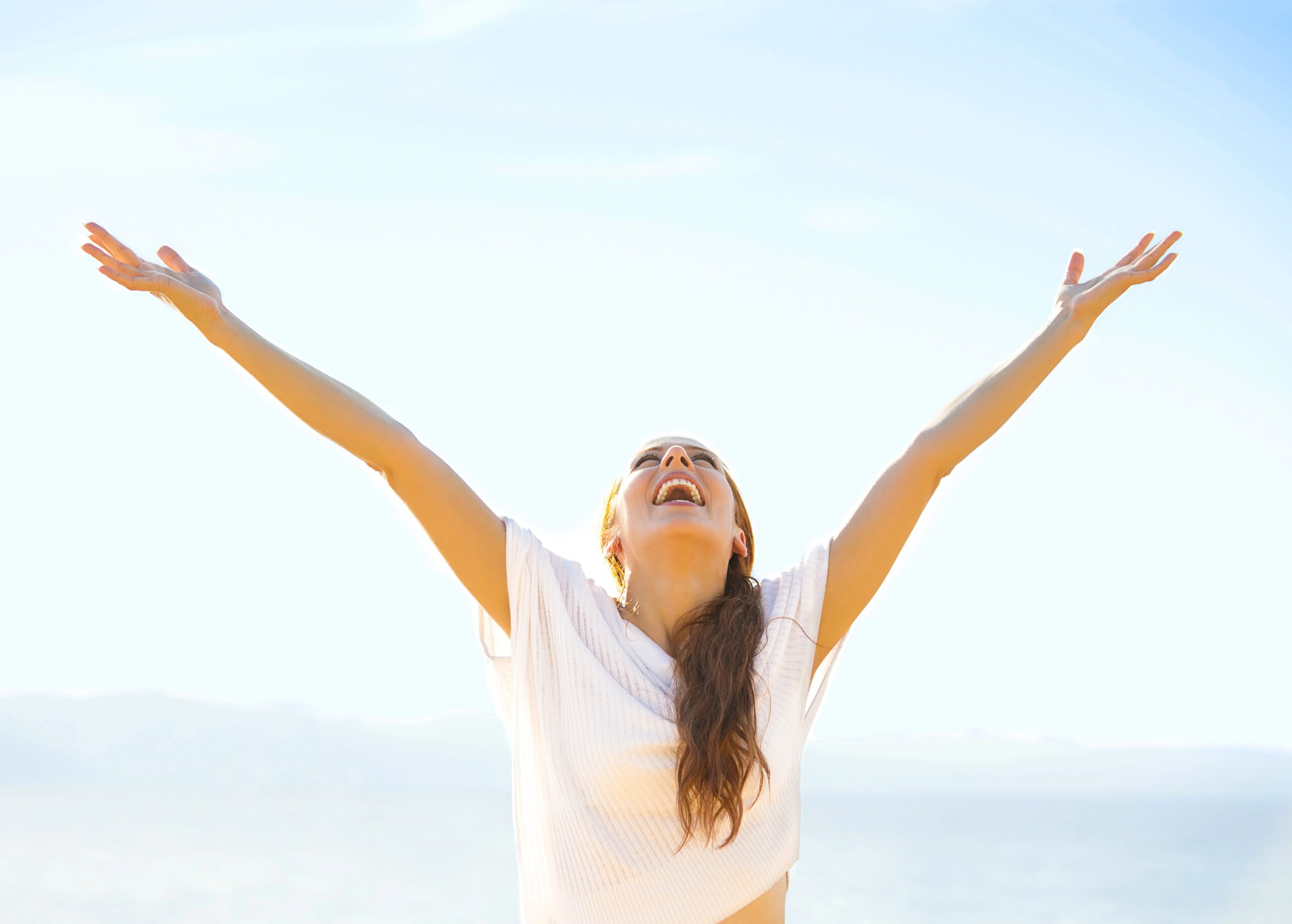 Positivity or positive mindset - happy woman with arms stretched up to the sky, symbolising embracing a positive life
