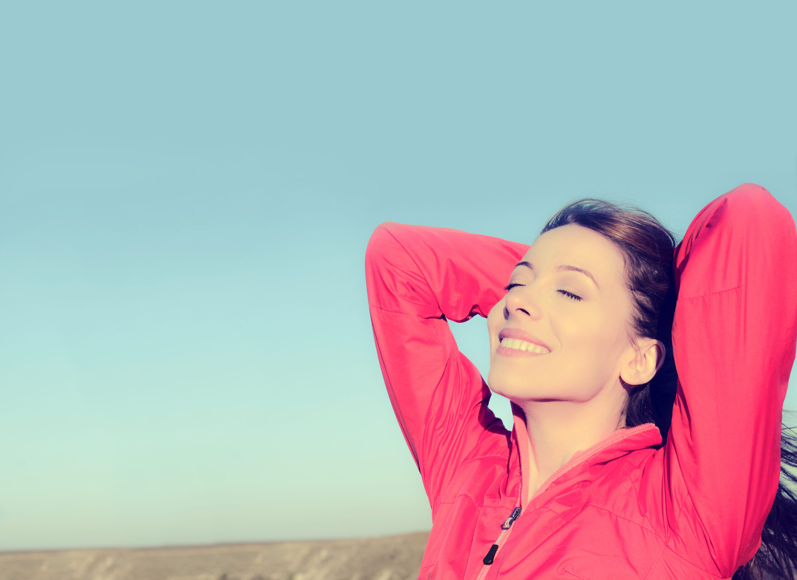 woman smiling, eyes closed, head tilted towards the blue sky. Simple habits for mental health 2023