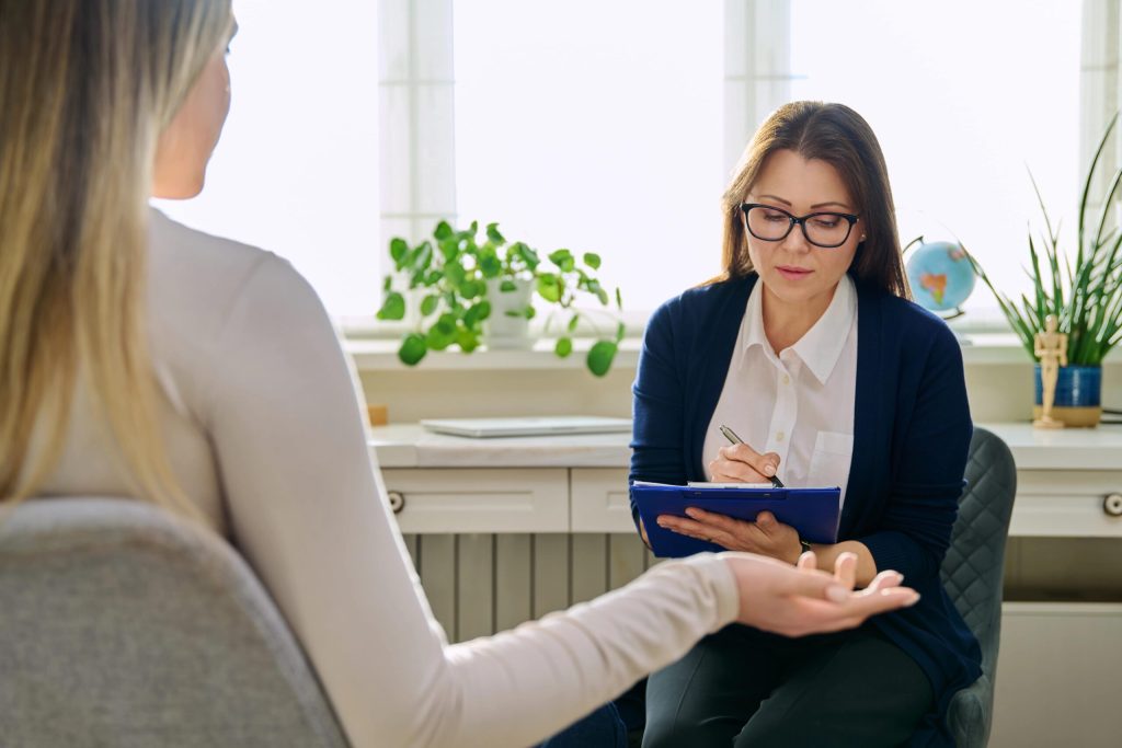 What Does a Mental Health Social Worker Do? 5 Mental health social worker. A woman speaking to a female mental health social worker holding a clipboard.