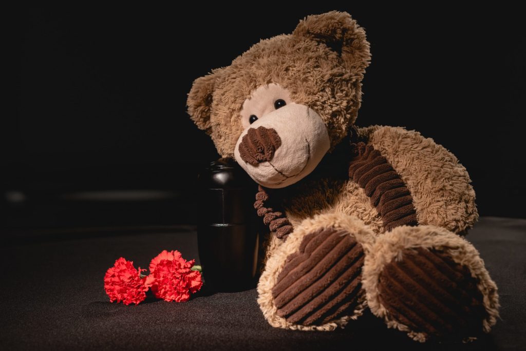 death of child, teddy bear leaning against urn