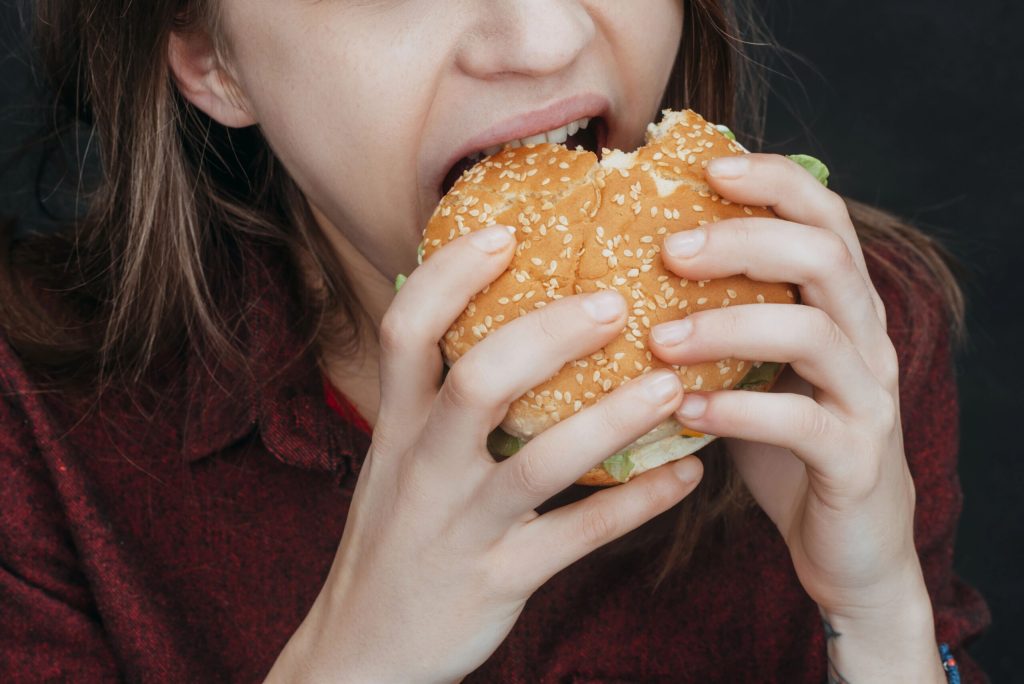 food addiction, woman eating a hamburger