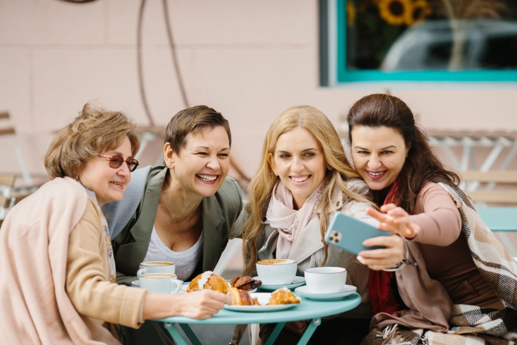 The Power of Connection: Why Social Interaction is Essential for Your Well-Being 11 Social isolation and the benefits of connection. Four middle aged women, happy, chatting over coffee at a cafe.